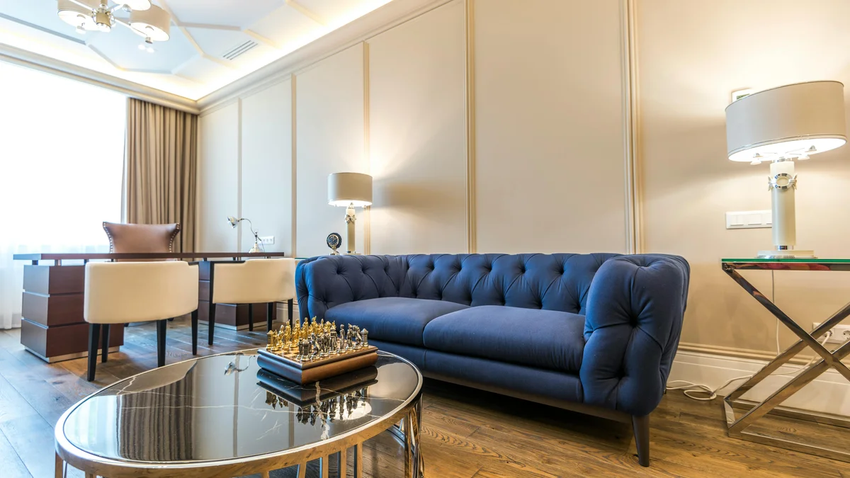 Sala de estar moderna e iluminada com sofá azul, decoração elegante e luz natural.