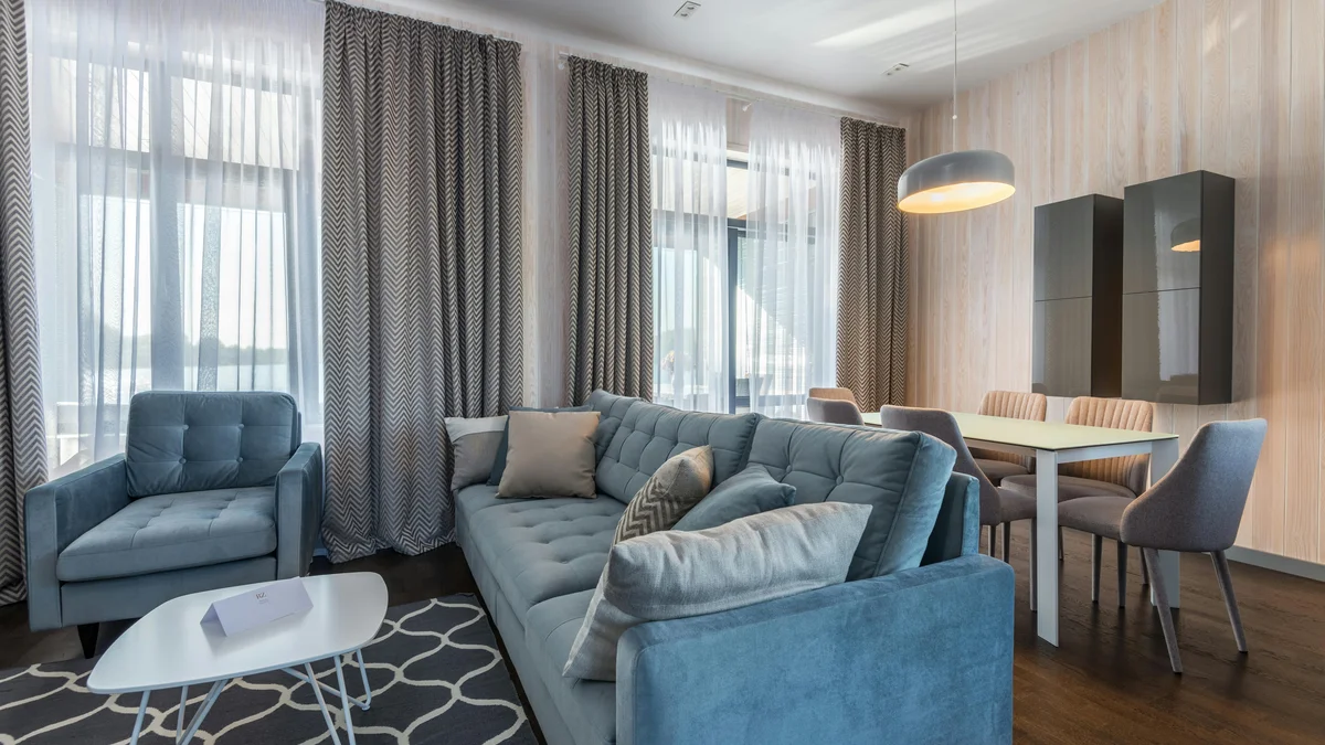 Sala de estar elegante com sofá azul, poltronas e decoração moderna.