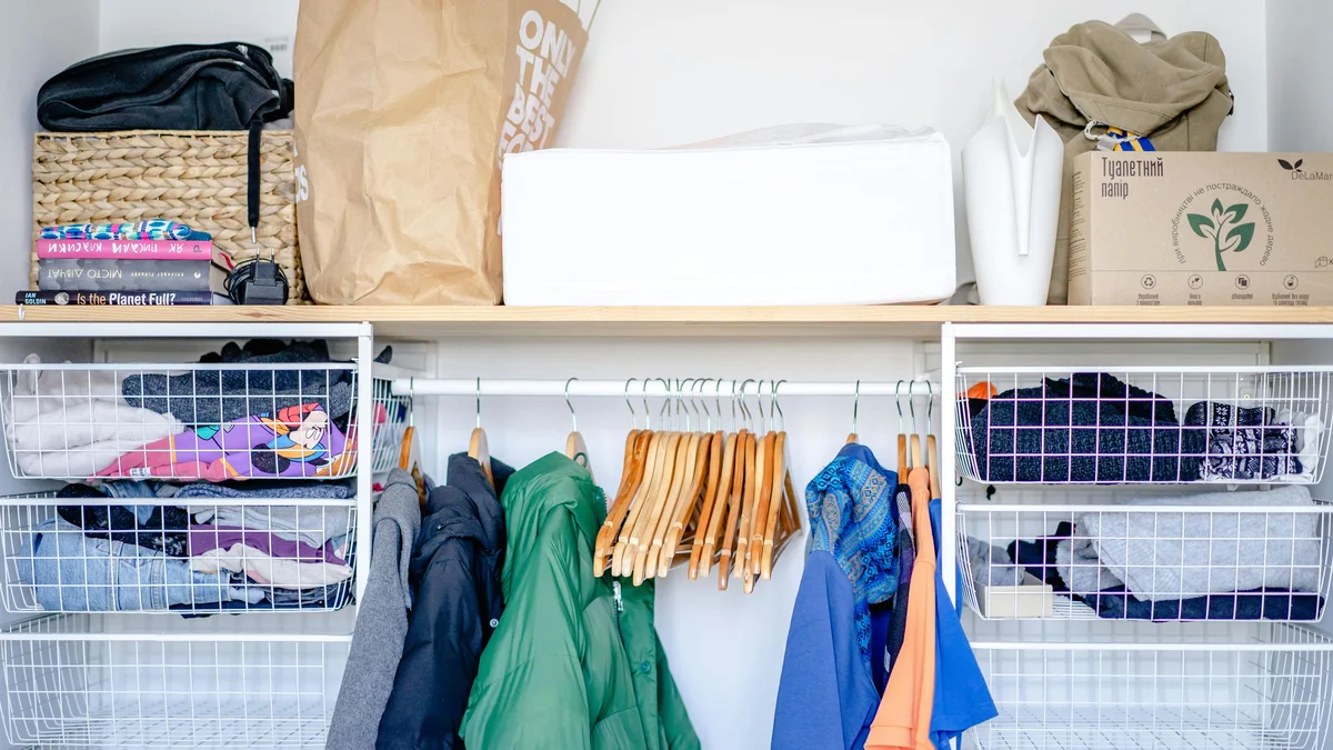 Um guarda-roupa aberto e minimalista com roupas modernas, cabides e cestos organizadores.