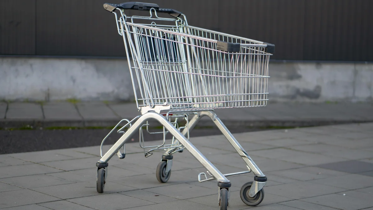 Carrinho de compras metálico solitário num estacionamento externo vazio, capturando a essência do consumismo.