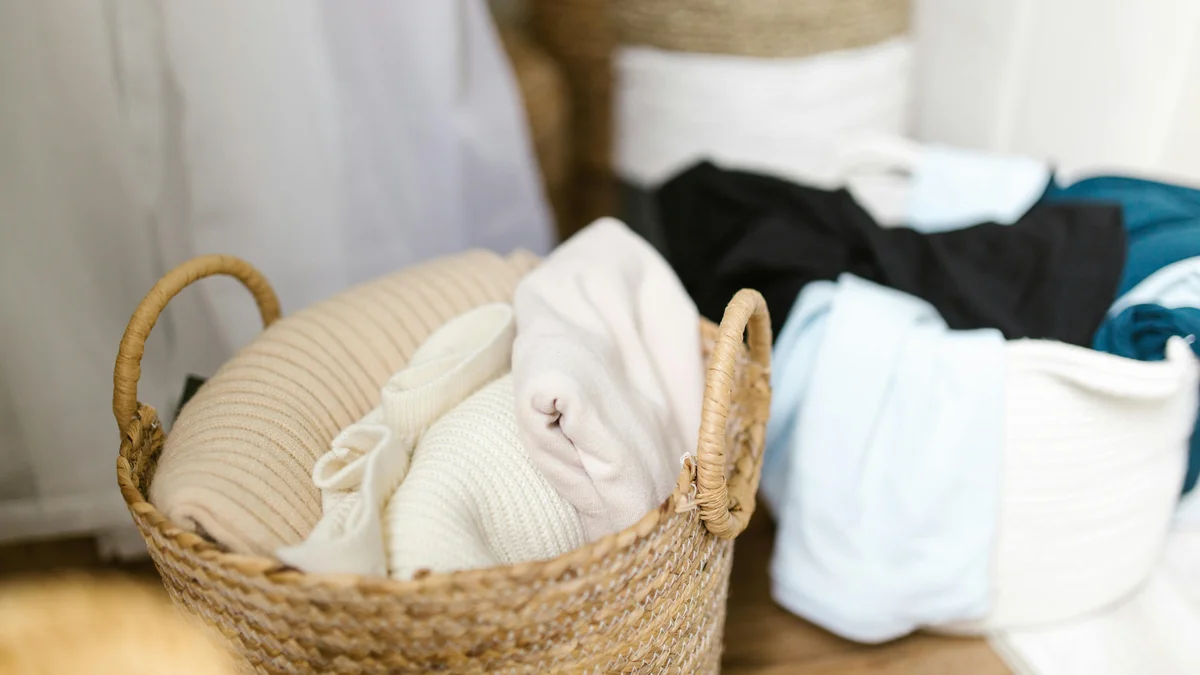 Roupas macias organizadas em cestos de roupa trançados, criando um ambiente interior acolhedor e arrumado.