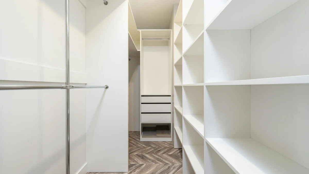 Closet moderno e elegante com prateleiras brancas e espaço de armazenamento, oferecendo um design interior limpo e organizado.