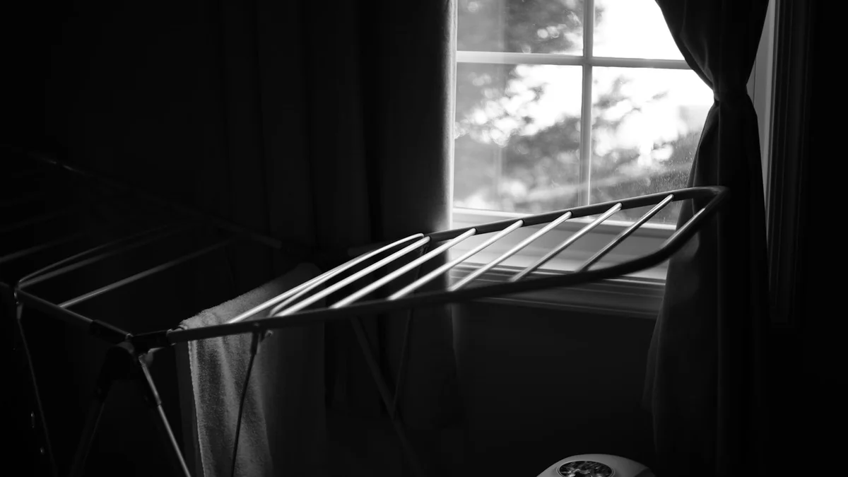 A black and white photo of a bed and a window Ilustração editorial secção 4 sobre melhor passadeira a vapor no formato