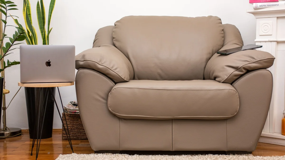 a brown leather chair sitting in a living room next to a laptop computer Ilustração editorial secção 1 sobre melhor