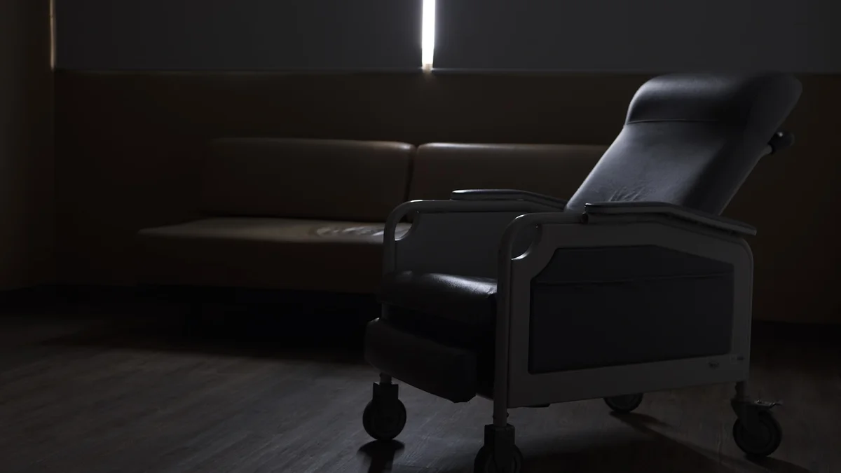 A darkened room with a chair is shown. Ilustração editorial secção 2 sobre melhor poltrona reclinável no formato