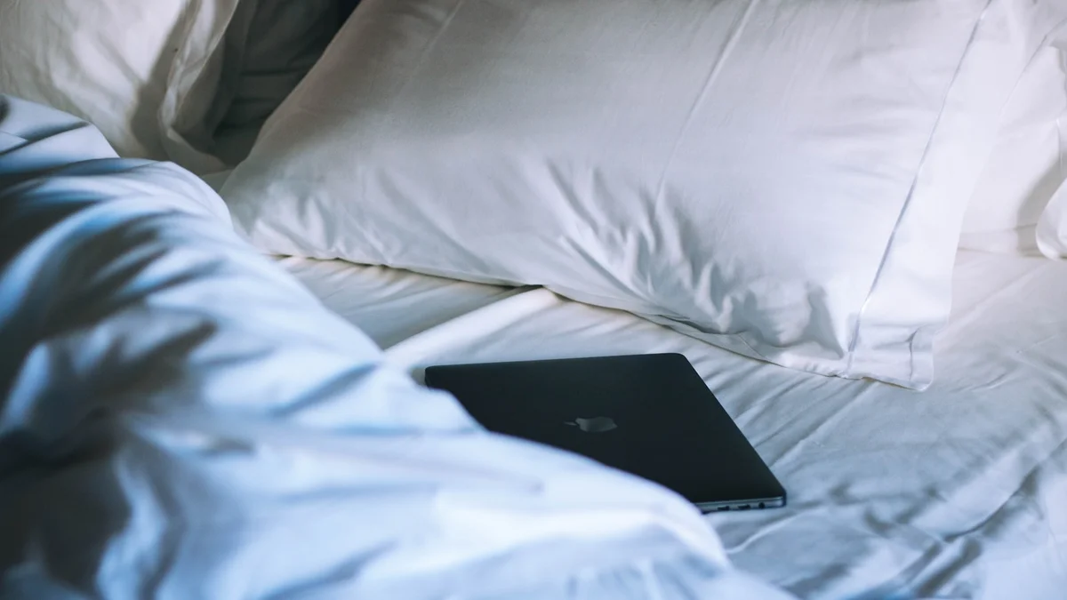 black MacBook on bed Ilustração editorial secção 1 sobre melhor travesseiro no formato paisagem 16 por 9 para artigo