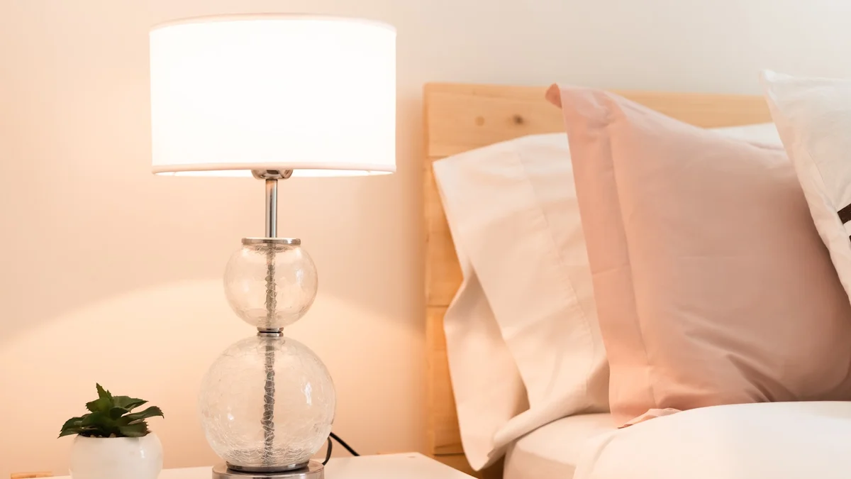 a lamp and a pillow on a table Ilustração editorial secção 1 sobre melhores abajures para quarto no formato paisagem 16