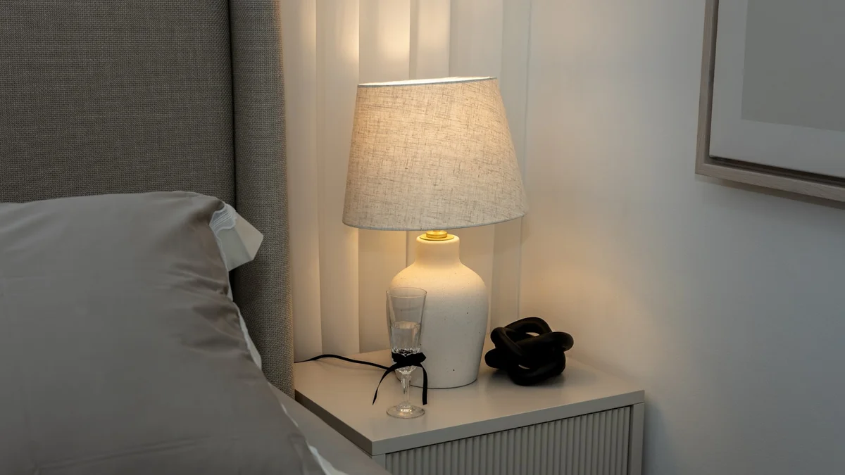 A bedside table with a lamp and decor. Ilustração editorial secção 3 sobre melhores abajures para quarto no formato