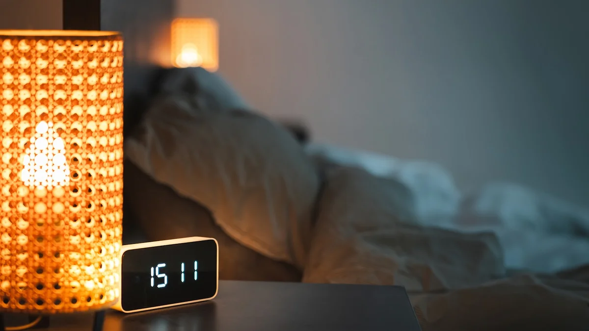 Relógio e abajur na cabeceira — imagem editorial (Unsplash) para abajures de quarto.