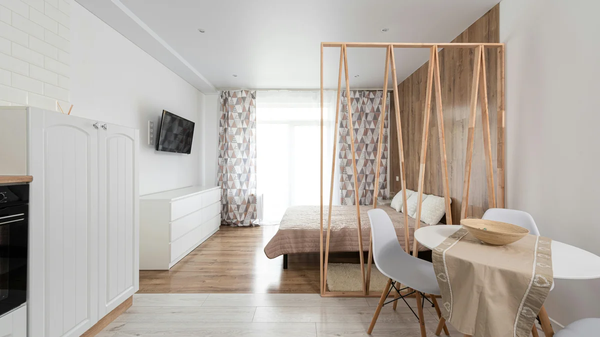 Design criativo de sala de jantar com mesa, cama e cômoda sob uma TV de tela preta em casa.
