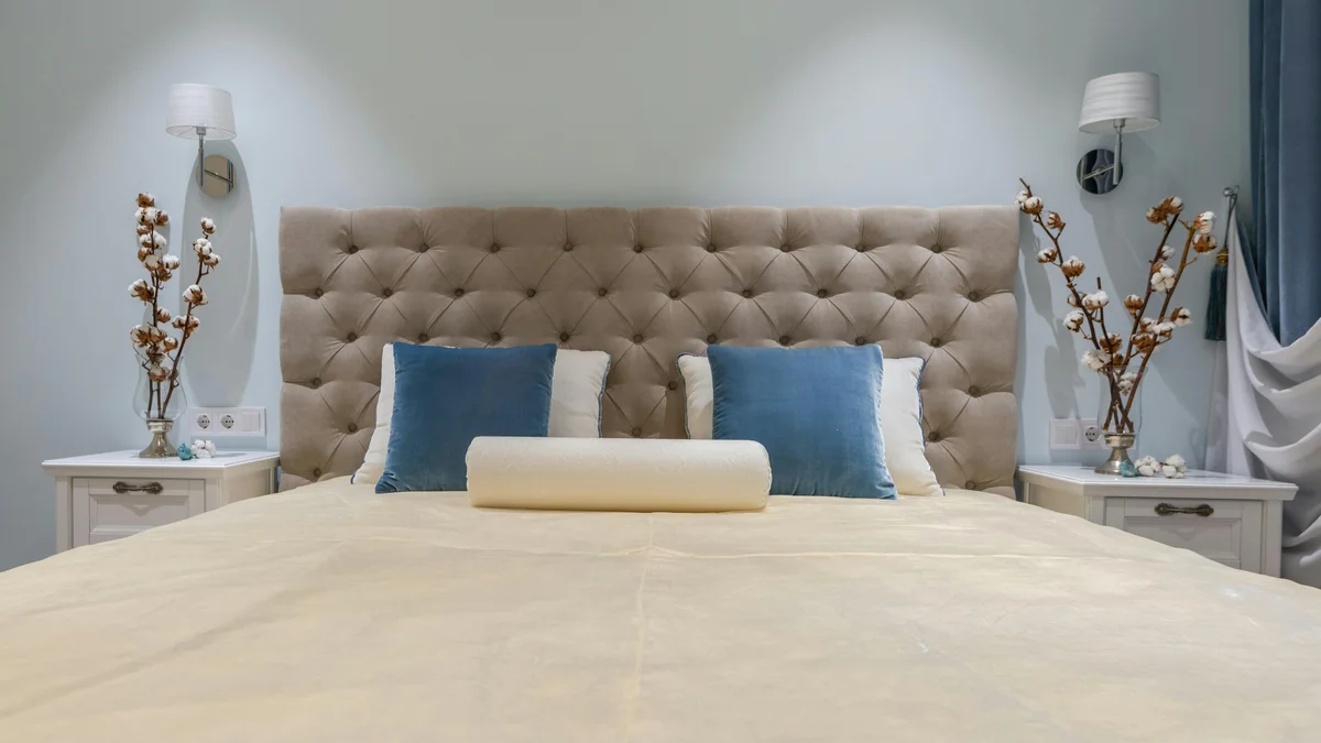 Cama king size confortável com pillow top, travesseiros e mesas de cabeceira decoradas com flores em um quarto aconchegante de estilo clássico.
