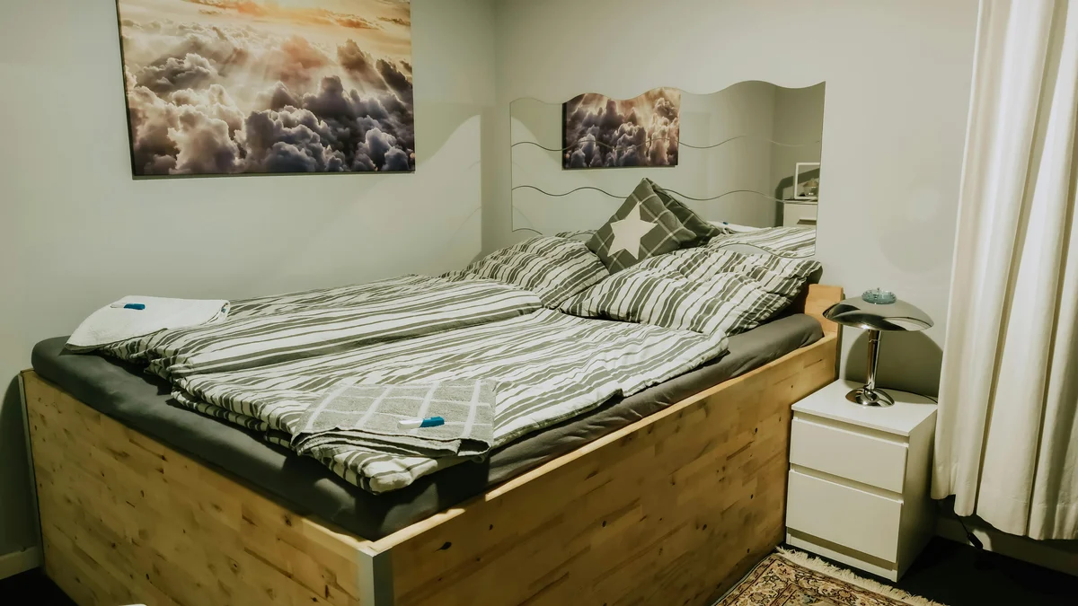 Interior de quarto moderno com cama de madeira, decoração estilosa e iluminação quente, criando uma atmosfera acolhedora e convidativa para o descanso.
