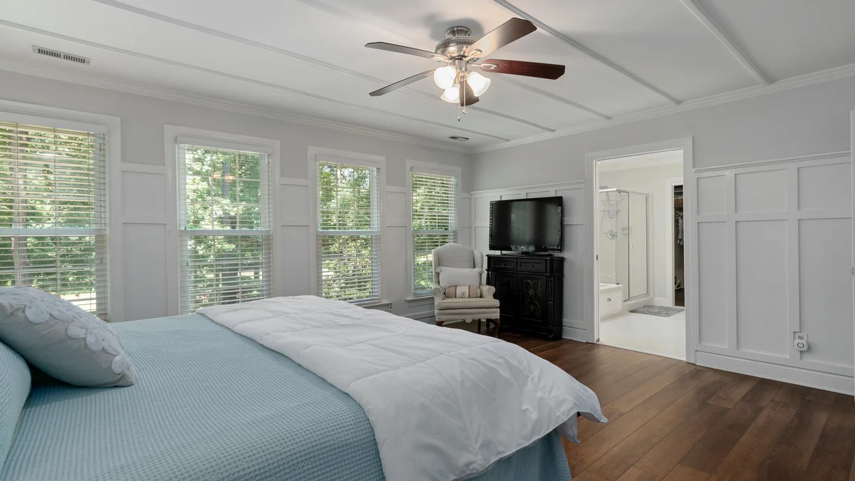 Quarto moderno e espaçoso com decoração elegante, cama aconchegante e luz natural abundante vinda de grandes janelas.